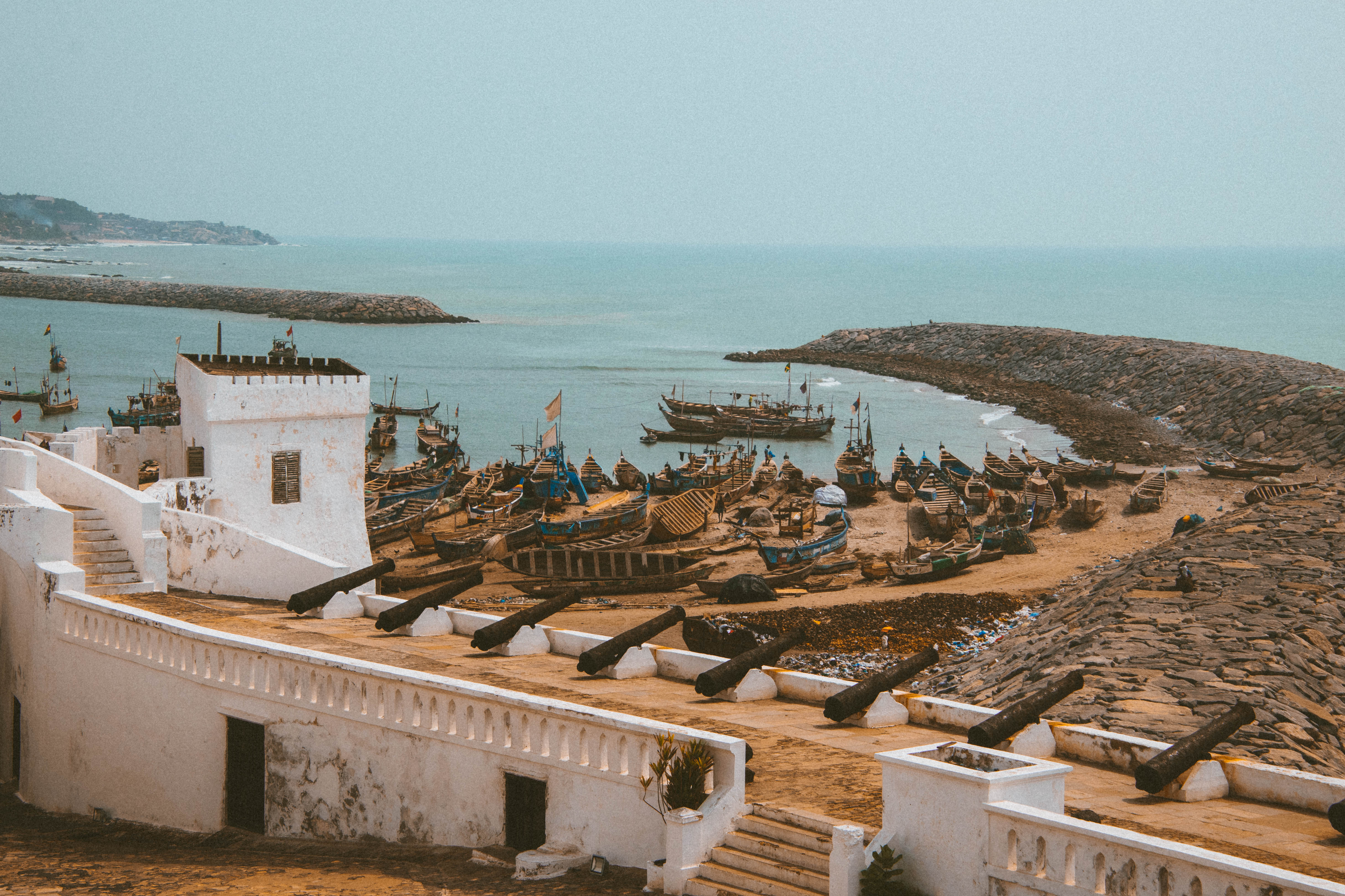 White-washed Cape Coast Castle interior courtyard with arched doorways, stairs and cannons