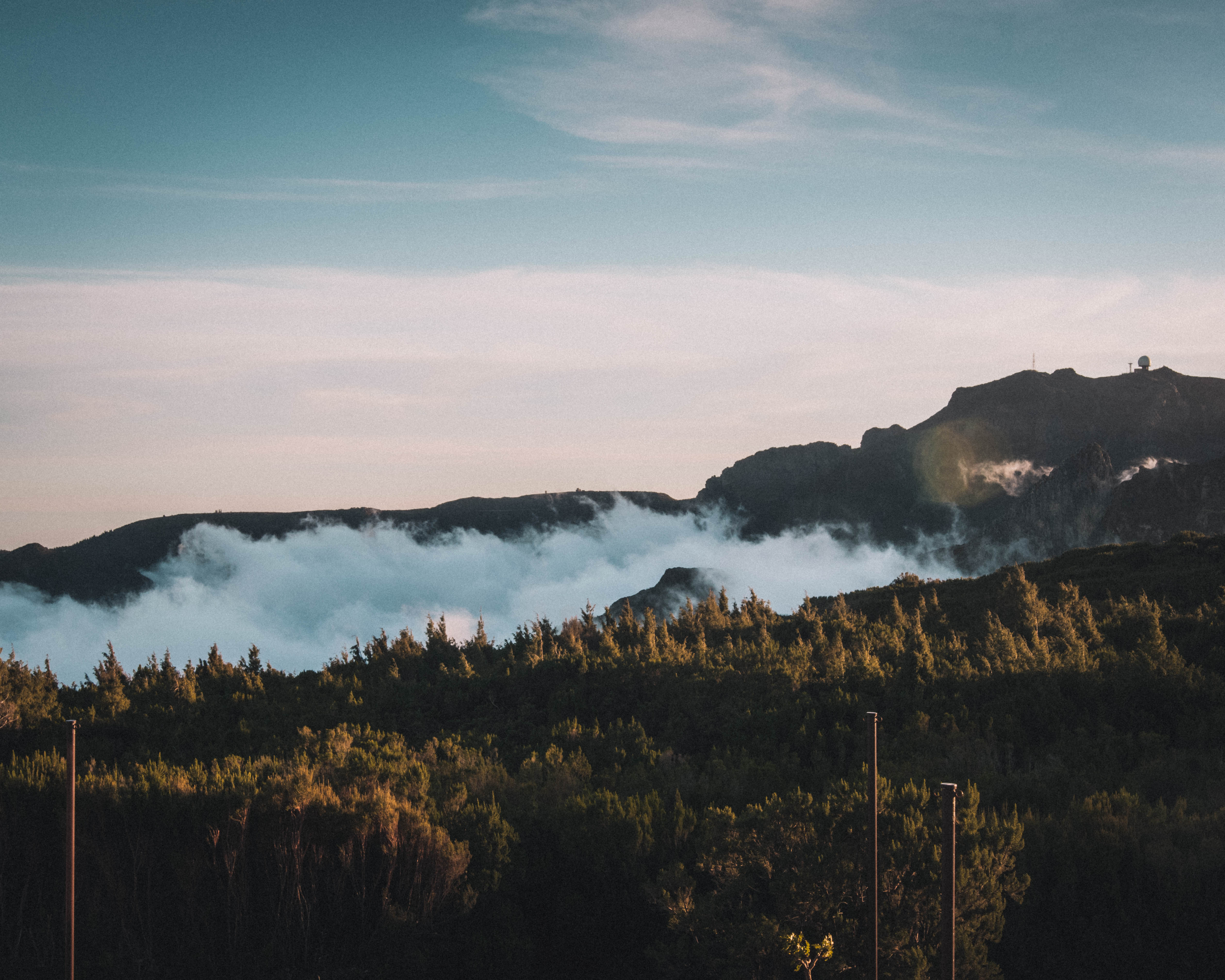 Person standing on rocky ridge overlooking vast cloud sea filling the valley