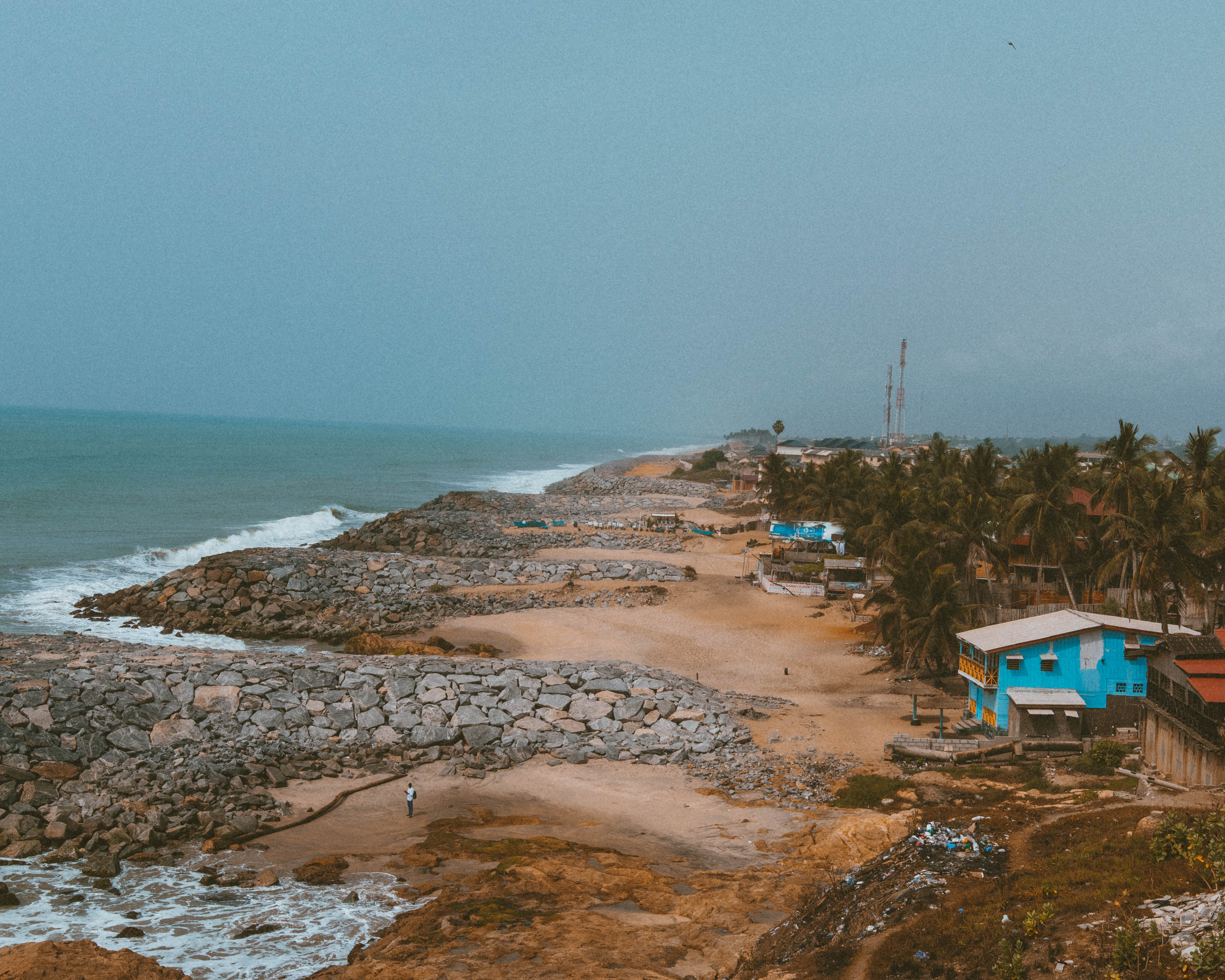 Fishing boats on sandy beach below Cape Coast Castle with cannons in foreground